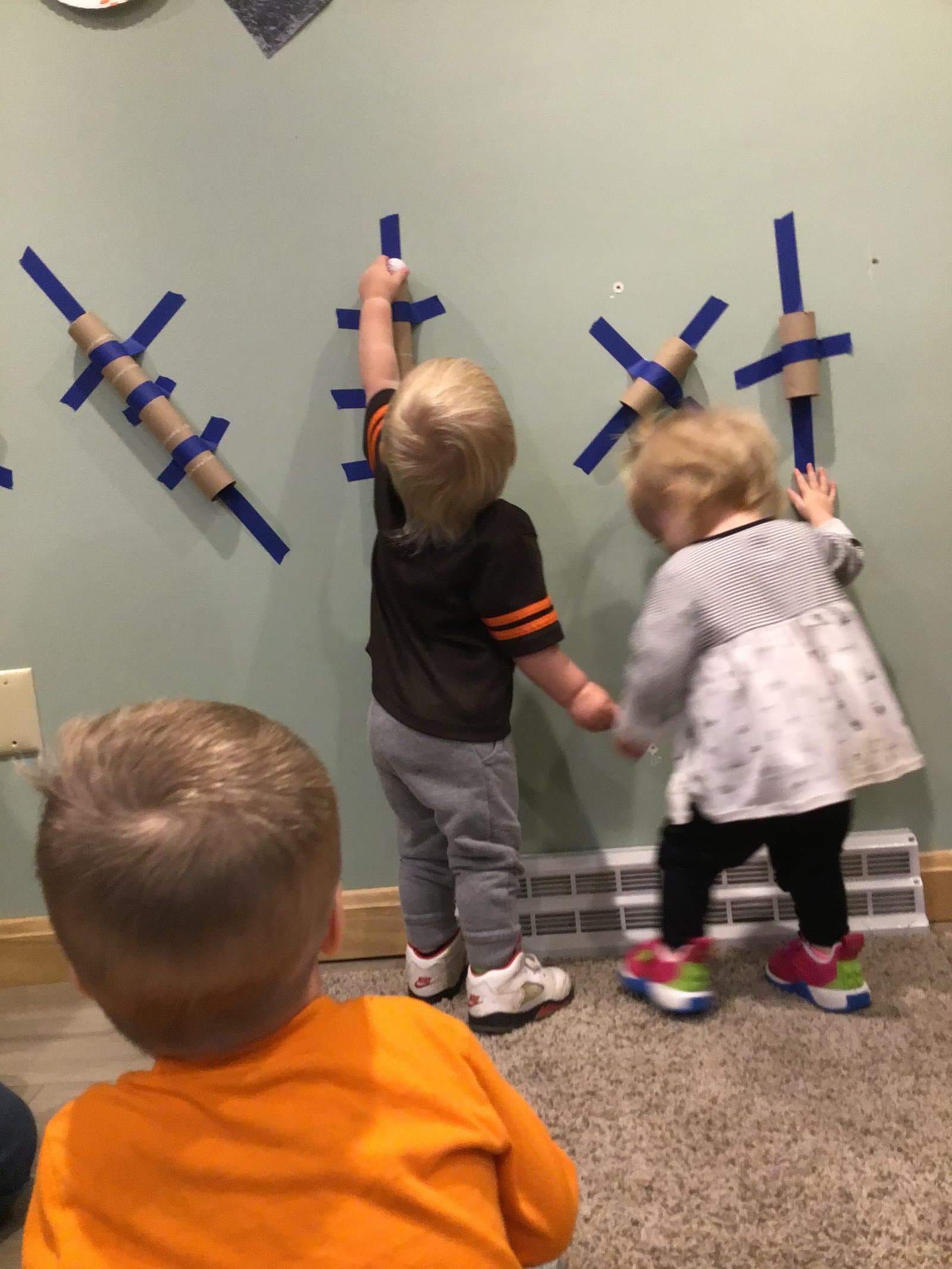 Little Acorns Sprouts toddlers exploring a tape and tube wall art project