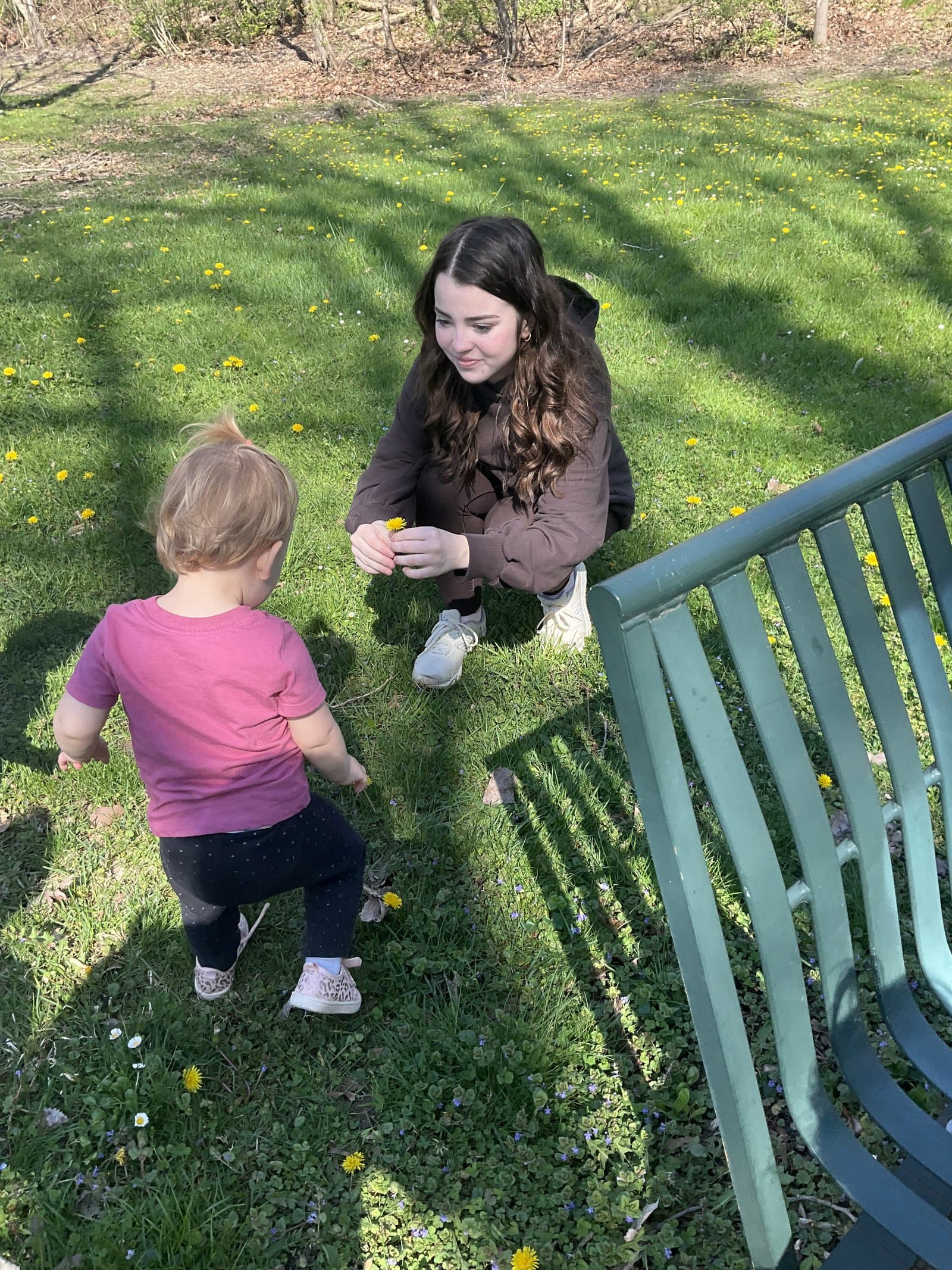 Little Acorns Life Saver — high school student teacher picking dandelions with a toddler